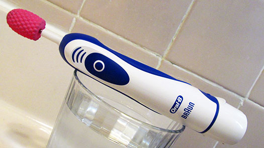 Viberry toothbrush vibrator resting on a glass of water